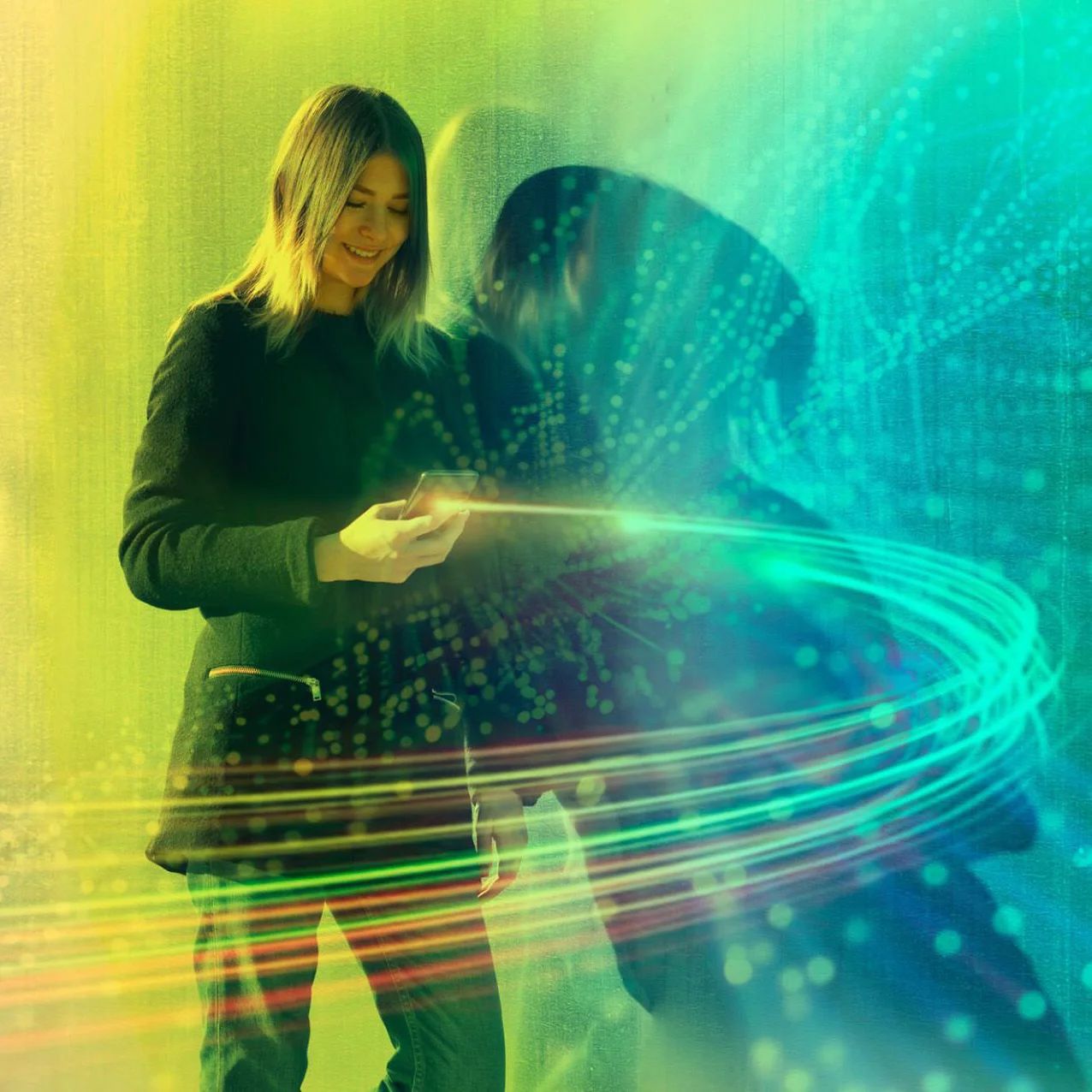 A woman standing against a wall, looking at her mobile phone with light lines streaking out of the device. 