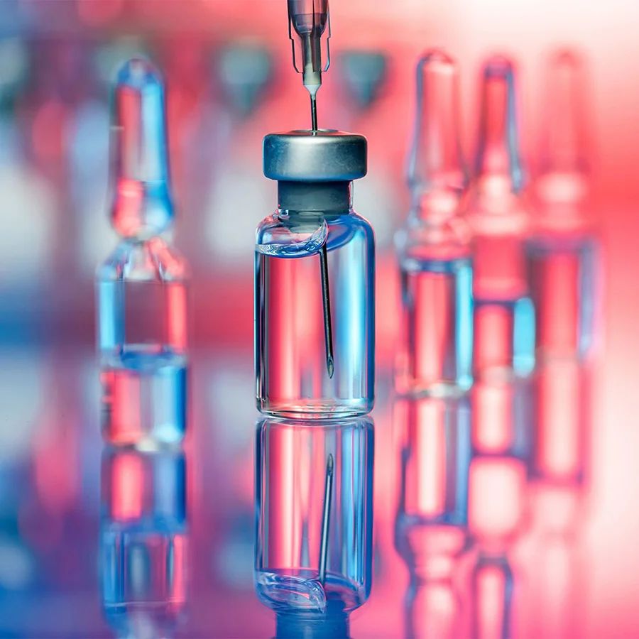 Syringe being inserted into a vial of clear liquid, with more vials in the background. The image relates to the article 'Collaboration on AI-powered Patient Safety Research Flags Drug Side Effects.'