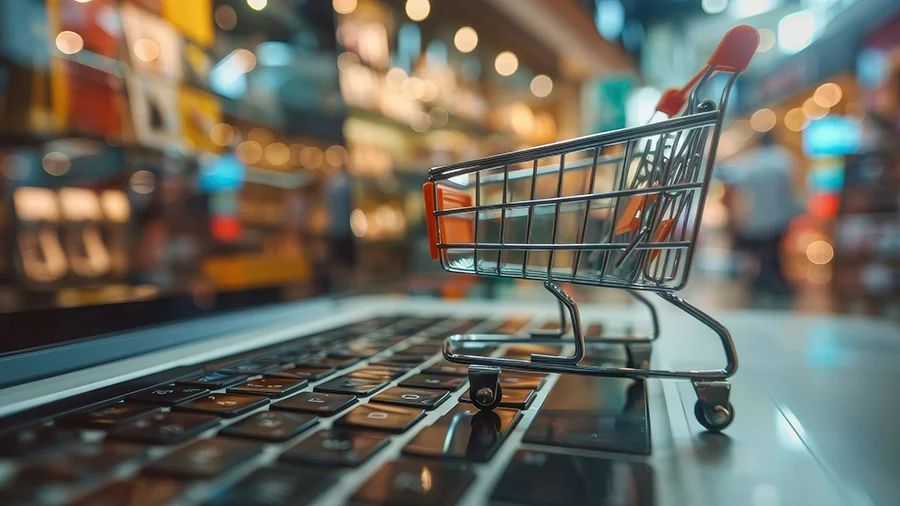 A tiny shopping cart rolling over a laptop keyboard.